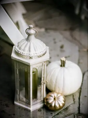 close up of white pumpkin and mini gold painted pumpkin with antique glass lantern