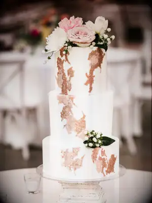 three-tier fall wedding cake decorated with rose gold abstract design and pink roses