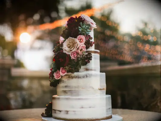 four-tier naked buttercream wedding cake with fall flowers in burgundy, pink and ivory colors