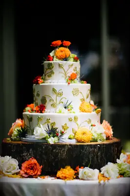elegant fall wedding cake decorated with gold piping and orange mums