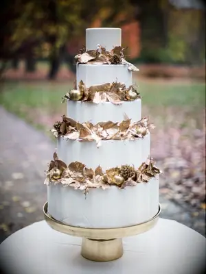 four-tier fall wedding cake with gold leaves in between each tier