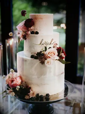 modern fall wedding cake with smooth buttercream frosting, dark pink roses, blackberries and custom last name topper