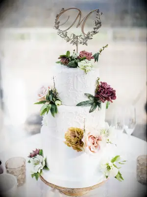 white fall wedding cake with hand-piped icing in floral design and fresh flower accents
