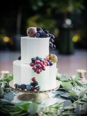 two-tier white wedding cake with purple grapes, blackberries, blueberries and miniature pears