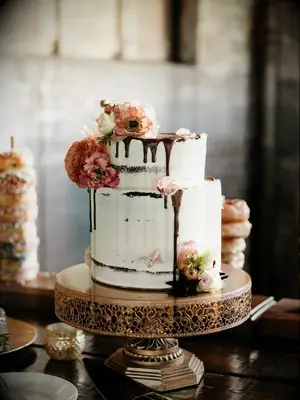 two-tier buttercream fall wedding cake with chocolate drip icing and pink and orange flowers