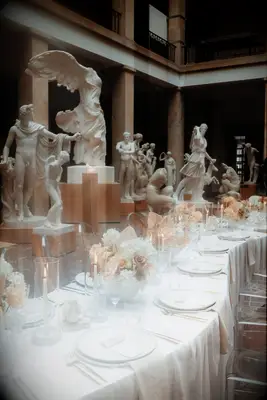 Serpentine table with white tablecloth and neutral flowers 