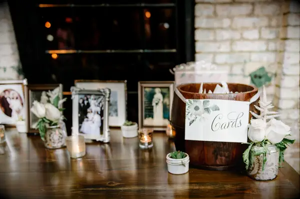 wedding welcome table decorated with framed family photos and wooden barrel repurposed as card box
