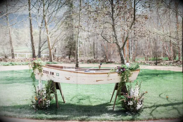wooden rowboat decorated with flowers and greenery repurposed into wedding gift table 