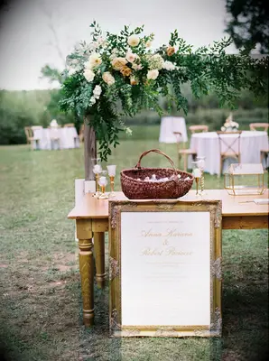 elegant wedding gift table with gold framed welcome sign, glass card box and wedding favors in woven basket