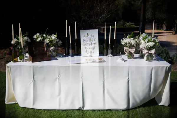 wedding gift table with white tablecloth, watercolor welcome sign, white flowers and white taper candles in wine bottles