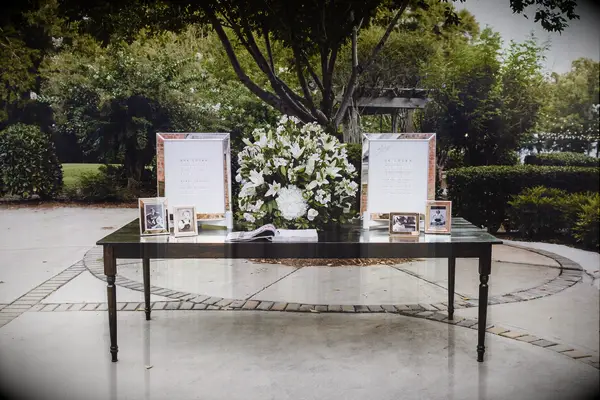 wedding gift table with large white lily centerpiece and childhood photos of the couple in silver frames