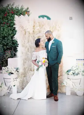 Bride and groom photoshoot in front of pampas grass wall.