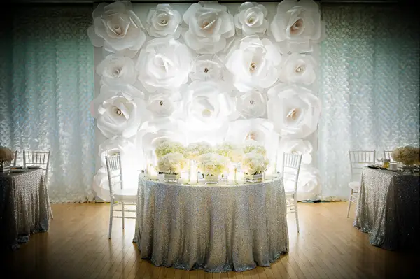 Large white paper flower wall behind a sweetheart table.