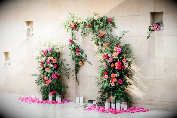 A vibrant pink and orange rose flower installation at a summer wedding.