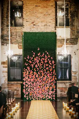 A tall green and peach wall of flowers at a couple