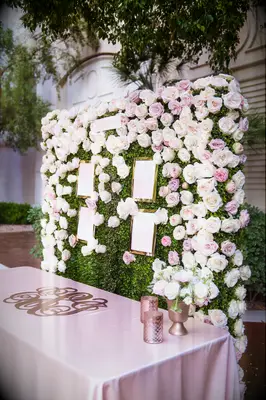 Pink and ivory rose floral wedding wall behind escort cards. 