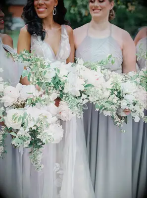 Bridesmaids in gray dresses holding green-and-white bouquets