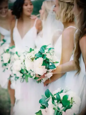 Bridesmaids in white dresses with white-and-green bouquets