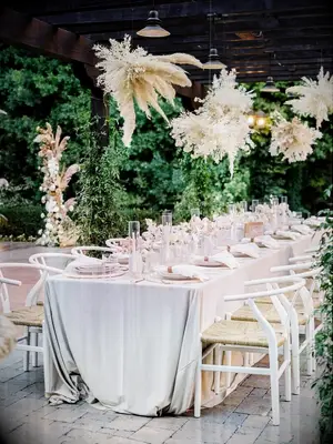 Boho reception tablescape under pergola with pampas grass chandeliers