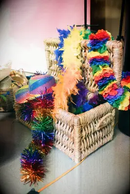 Rainbow-hued hats and boas in wicker box