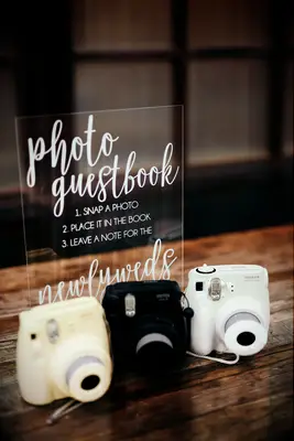 Polaroid cameras sitting on table with acrylic sign