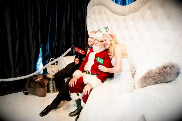 Couple poses in a Christmas-themed photo booth. 