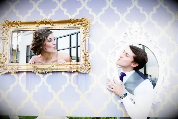 Couple poses in picture frame props for a wedding photo booth. 