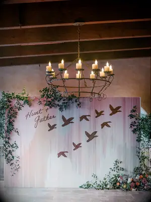 Pastel pink backdrop with bird details underneath chandelier