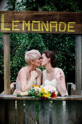 Couple shares a sweet kiss at a lemonade stand photo booth prop. 