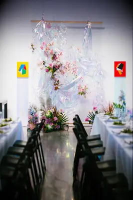 Irridescent photo booth backdrop with pink flowers. 