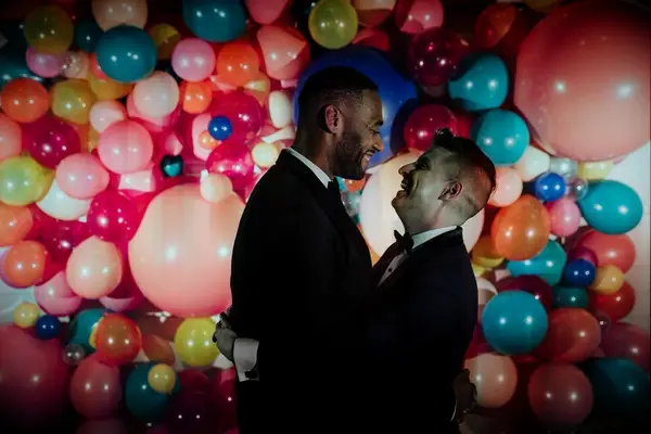 Couple sharing embrace in front of balloon wall