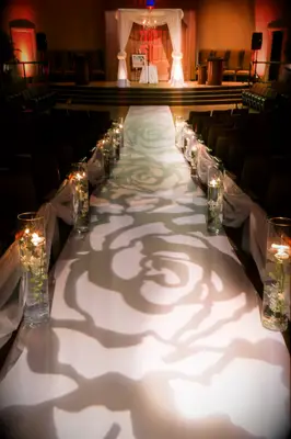 Beautiful lighting projects a rose-print onto the ceremony aisle. 