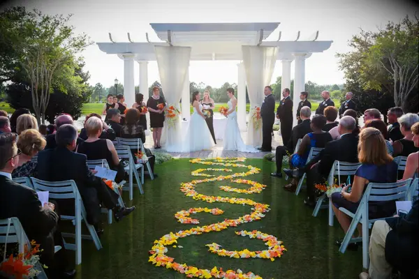Ceremony aisle lined with orange and yellow flower petals. 