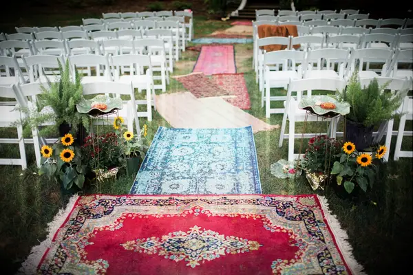 Aisle lined with mismatched colorful rugs. 