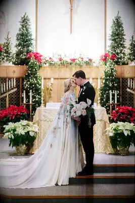 Couple sharing kiss in church surrounded by poinsettias