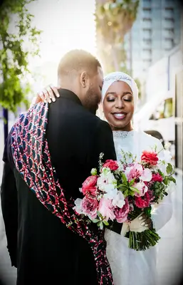 bride holding pink and fuchsia wedding bouquet hugs groom
