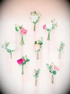 pink and white wedding boutonnieres against a light pink backdrop