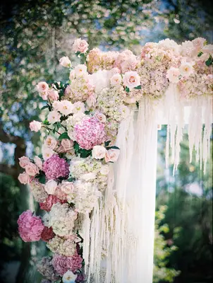 close-up of wedding ceremony arch decorated with pink hydrangeas, blush roses, and white amaranthus