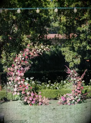 outdoor wedding ceremony backdrop with pink roses and astilbe in crescent moon shaped arch