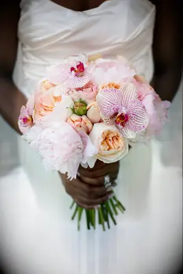 bride holding small wedding bouquet with pink orchids, blush garden roses and light pink peonies