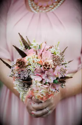 small bridesmaid bouquet with pink alstroemeria, wax flowers, scabiosa pods, and brown feathers