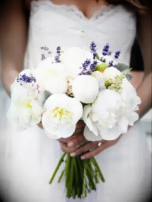 A bride holds a bubbly bouquet of white peonies and lavender.