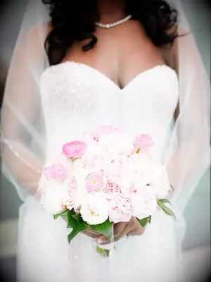 A bride holds a bouquet of ombré pink peonies.
