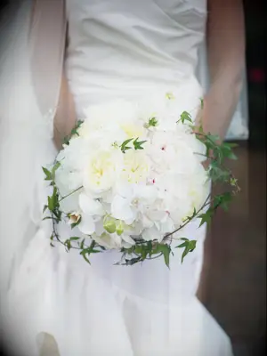A bride holds a burgeoning bouquet of stunning white peonies.