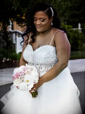 A bride holds a pale lavender and white bouquet.