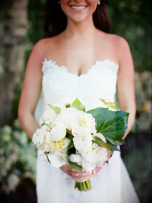A bride holds a stunning bouquet of lilies and white peonies.