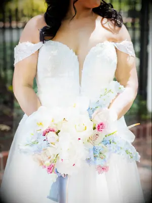 A bride holds a stunning springtime bouquet of pale blues, creams and pinks.