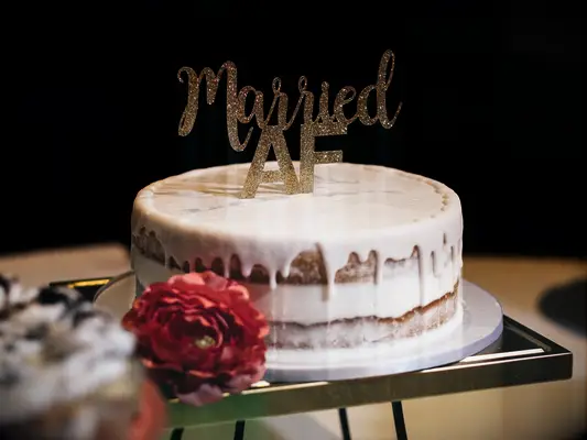 funny one tier wedding cake with drip vanilla icing and married AF cake topper in gold glitter letters