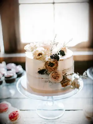 rustic one tier wedding cake with mauve, burgundy and blush roses on glass cake stand