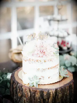 one tier wedding cake with pink dahlia, succulents and gold calligraphy mr. & mrs. topper